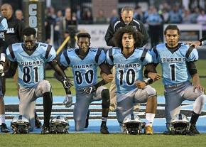 Lansing Catholic High School football players take a knee during the national anthem